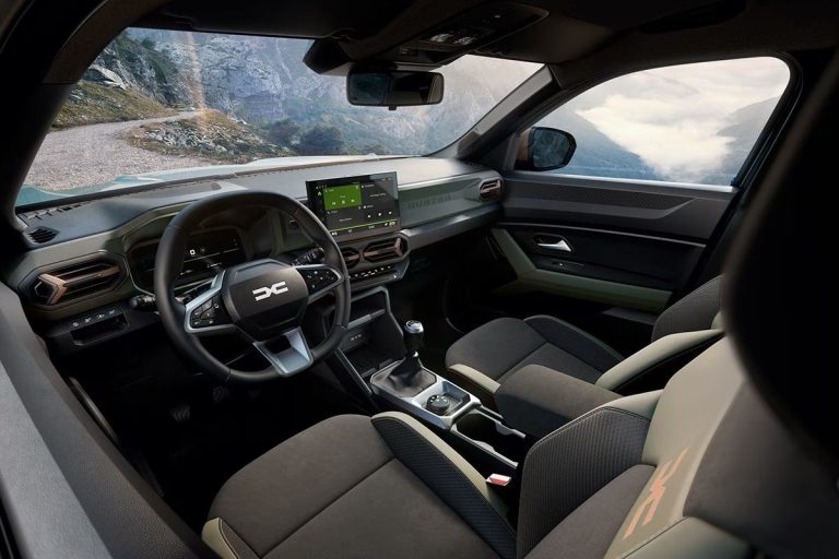 Dacia Duster leasen - dashboard met stuurwiel, bergachtig kustzicht door de voorruit