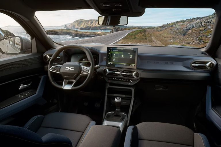 Dacia Duster leasen - dashboard met Duster-belettering op het portier, kustweg door de voorruit