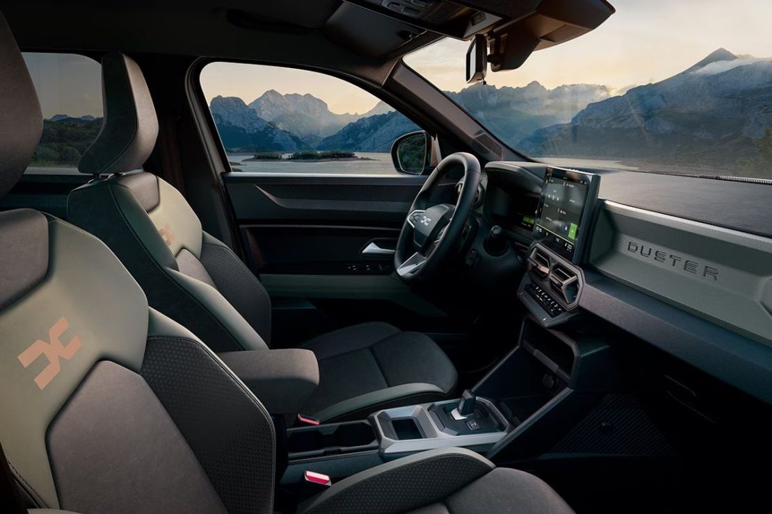 Dacia Duster leasen - dashboard en voorstoelen met Duster-belettering op het portier, bergzicht door het raam