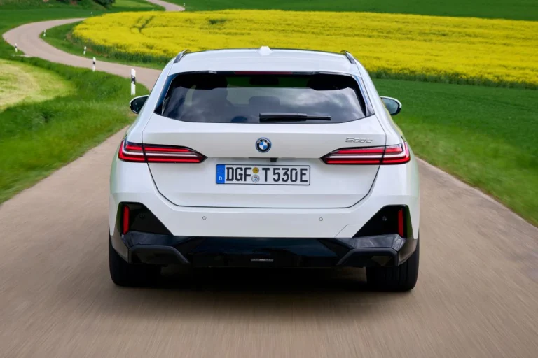 BMW 5-Serie Touring leasen - achteraanzicht tijdens het rijden op een landweg door een geel bloemenveld