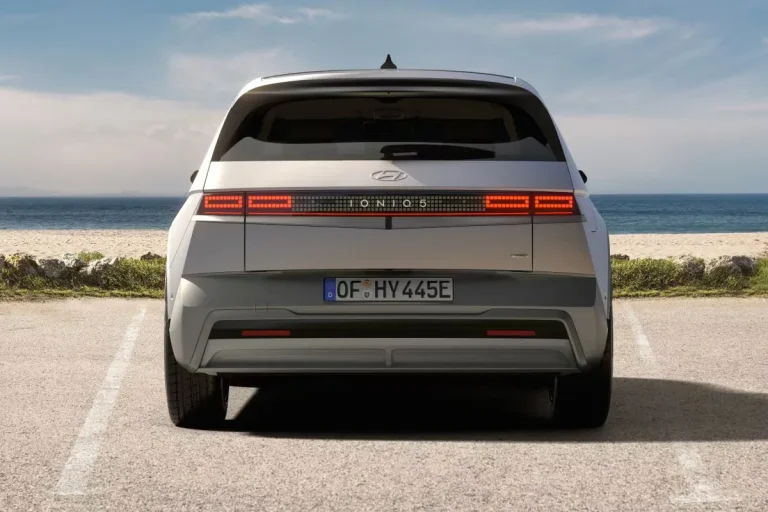 Hyundai IONIQ 5 leasen - achteraanzicht met doorlopende achterlichtbalk aan zee