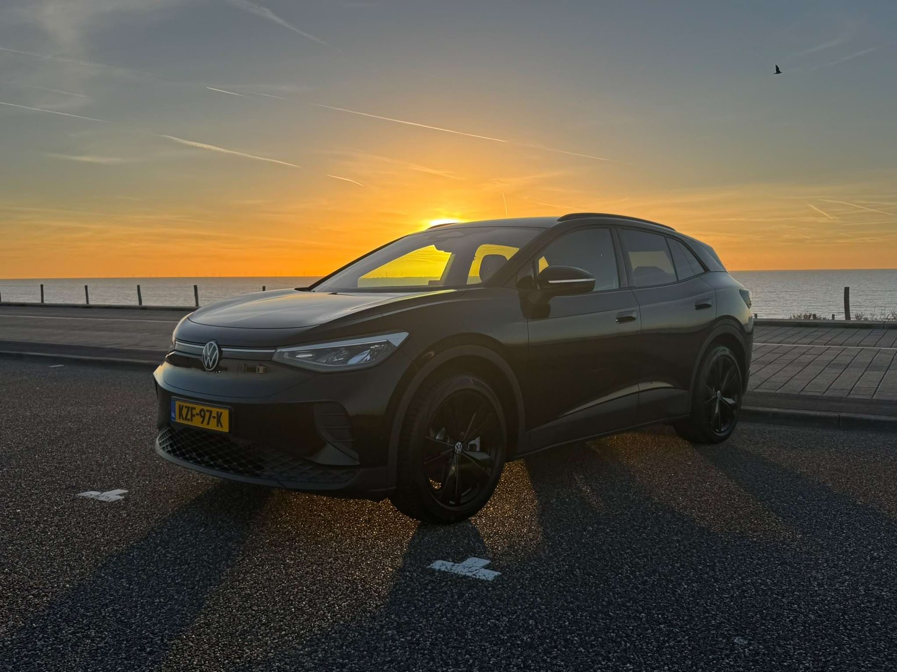 Afgeleverde Volkswagen ID.4 van een LeaseRoute-klant bij zonsondergang aan zee