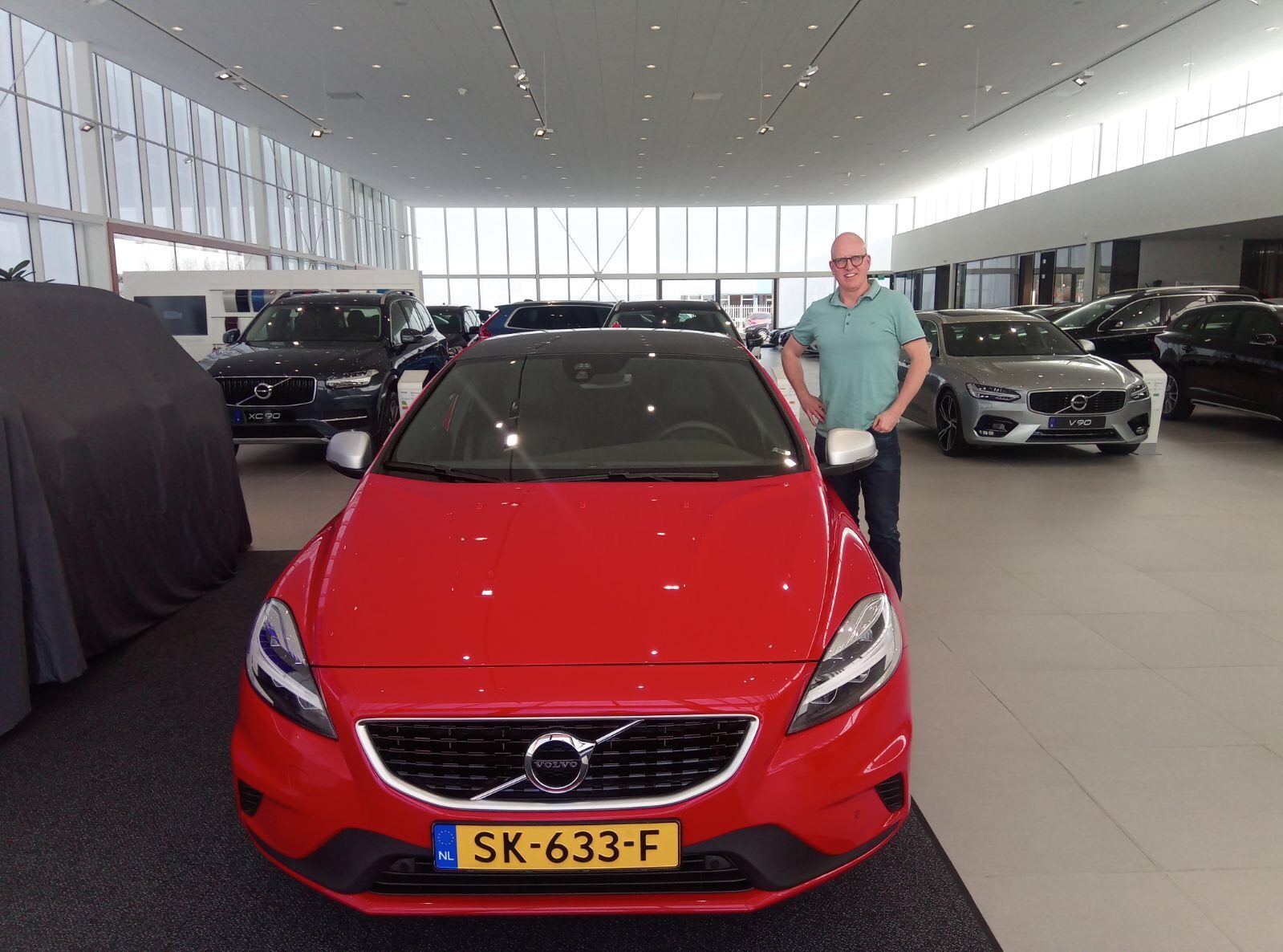 LeaseRoute-klant bij de afgeleverde rode Volvo V40 in de showroom