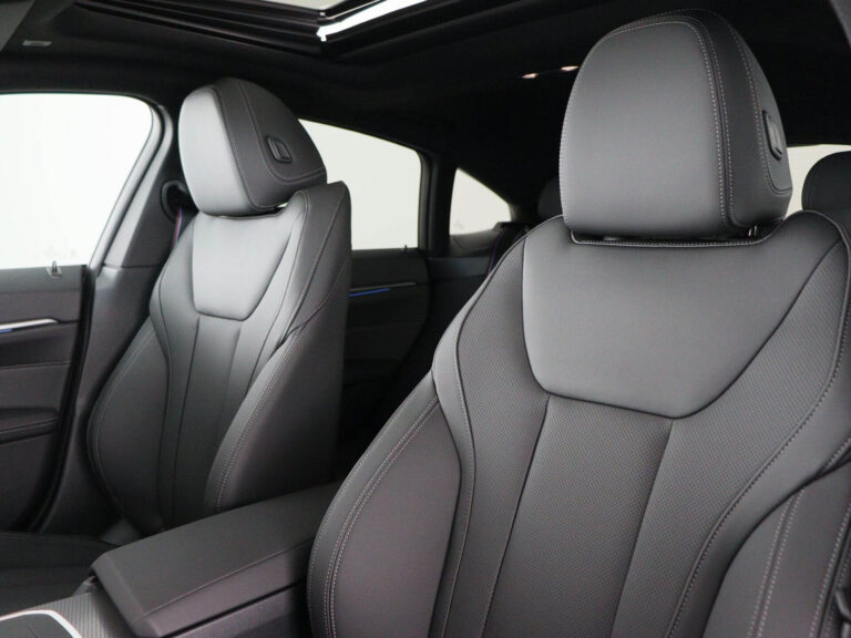 BMW i4 Occasion Lease - close-up van de voorstoelen in zwart leer met blauw stiksel en panoramadak
