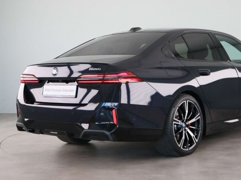Gebruikte BMW 5-Serie Leasen - schuin achteraanzicht met 520i-badge op studio-achtergrond