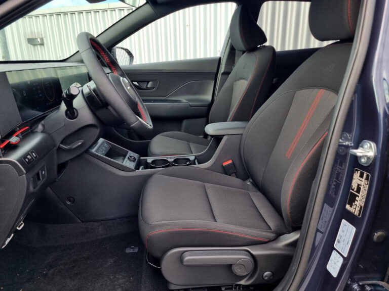 Hyundai Kona Zakelijk Leasen - voorstoelen met rood stiksel, gezien vanuit het geopende portier