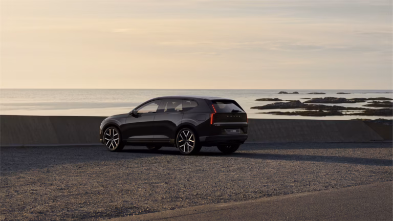 Zakelijk leasen Volvo EX60 Plus - schuin achteraanzicht aan de kust bij zonsondergang