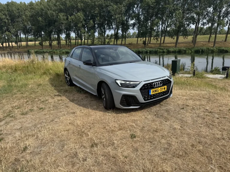 Audi A1 Sportback, schuin van voren links, wit, geparkeerd op een zandpad langs water en bomen