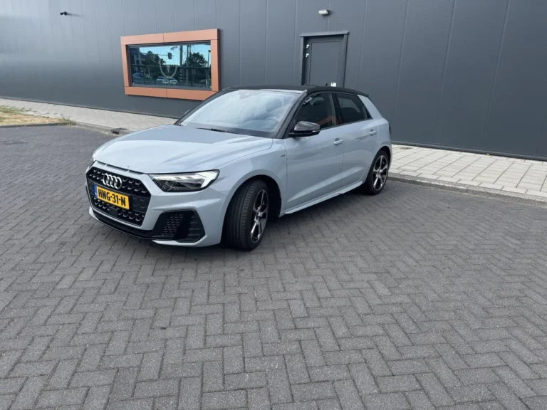 Audi A1 Sportback, schuin van voren links, witte sedan geparkeerd op grijs terrein