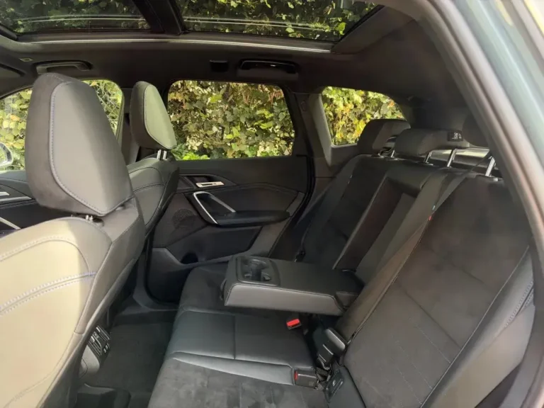 BMW iX1, achterbank met blauw stiksel, gezien vanaf de voorstoel
