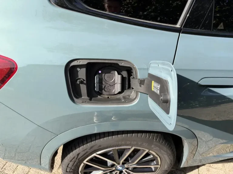 BMW iX1, geopende laadklep met AC- en DC-aansluiting op het rechter achterspatbord