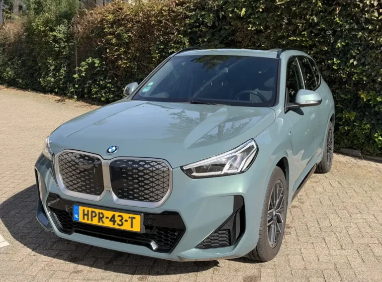 BMW iX1 occasion lease, Cape York Green iX1 eDrive20 M Sport schuin van voren links met M-bumper en 18-inch velgen