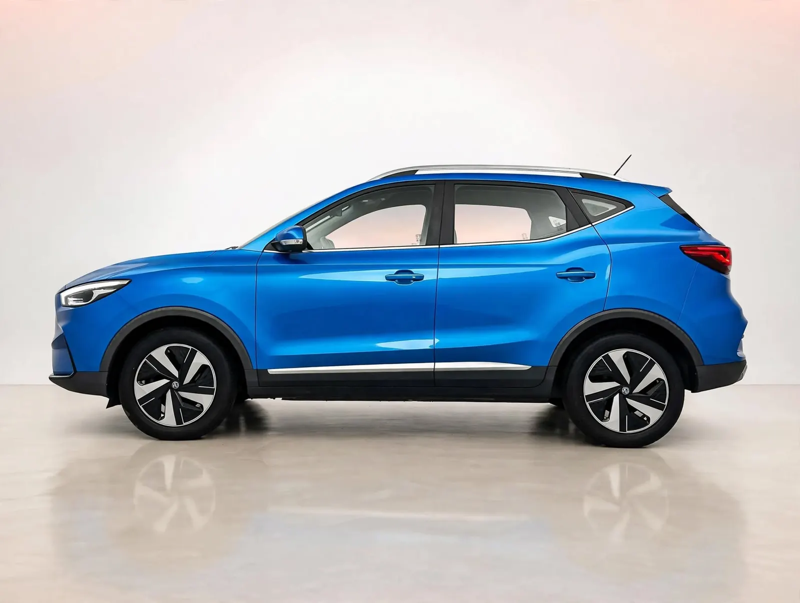 Blauwe elektrische MG ZS, zijaanzicht in een studio met witte lichtmetalen velgen